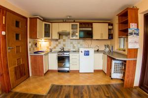 kuchnia z białymi urządzeniami i drewnianymi szafkami w obiekcie noclegi pokoje gościnne kwatery pracownicze Dobranocka w mieście Sieradz