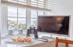 a desk with a television and croissants and a plate of food at Lundy Lookout 5 minutes drive to beach Hot tub in Westward Ho