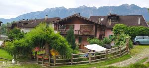 a house with a fence in front of it with mountains at B&B Al Larice in Strigno