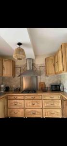 a kitchen with wooden cabinets and a stove top oven at Le Kerioubet - B&B au cœur du Pays d’Auge in Saint-Martin-de-la-Lieue