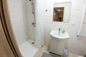 a white bathroom with a sink and a shower at noclegi pokoje gościnne kwatery pracownicze Dobranocka in Sieradz