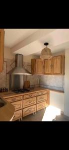 a kitchen with wooden cabinets and a stove top oven at Le Kerioubet - B&B au cœur du Pays d’Auge in Saint-Martin-de-la-Lieue