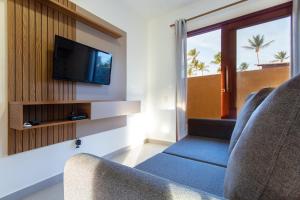 a living room with two chairs and a flat screen tv at Pousada Spa dos Amores in São Miguel do Gostoso