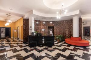 a lobby with a red chair and a table and a brick wall at Ibis Meknes in Meknès