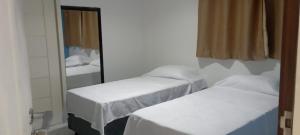 Cette chambre comprend 3 lits en face d'un miroir. dans l'établissement Pousada Ponta Negra, à Natal