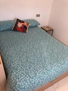 ein Bett mit einer grünen Bettdecke und einem Kissen darauf in der Unterkunft Apto. BLAIA in Irún