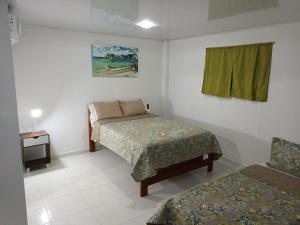 a bedroom with a bed and a table and a window at LodgeFabi'sPlace in San Andrés