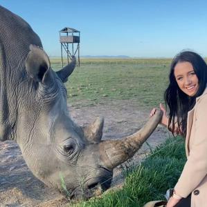 a woman is standing next to a rhino at ParkView Safari Lodge in Colchester