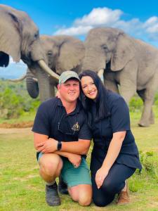 a man and woman posing in front of elephants at ParkView Safari Lodge in Colchester