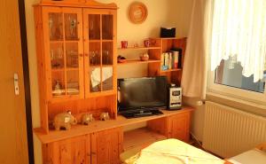 a living room with a tv and a wooden cabinet at Villa Helvetia in Bad Elster