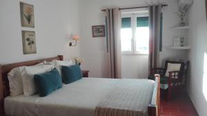 a bedroom with a bed with blue pillows and a window at Casa De Terena in Terena