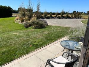 a patio with a table and chairs and a road at Ra-ata Farm in Rangiora
