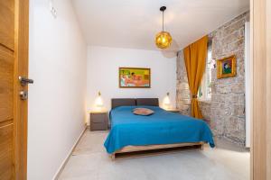 a bedroom with a blue bed and a stone wall at IDA ARTS APARTMENTS in Zadar