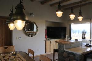 a dining room with a table and a television and lights at La Carrera Villas, Atamisque. Tupungato, Mendoza. in Ciudad Lujan de Cuyo