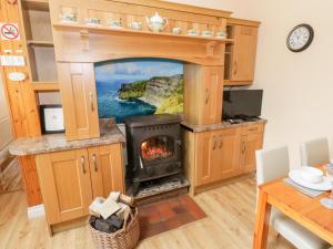 a fireplace in a kitchen with a view of the ocean at Cherry Tree Cottage in Ballintober