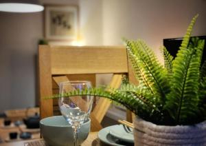 a table with a wine glass and a potted plant at Japanese Style MUJI Two-Bedroom Apt in Swansea