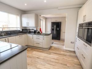 a kitchen with white cabinets and a black refrigerator at Beachway in Prestatyn