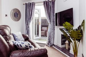 FlookburghにあるWillow Chalet near Cartmel & Lake Windermereのリビングルーム(革張りのソファ、暖炉付)