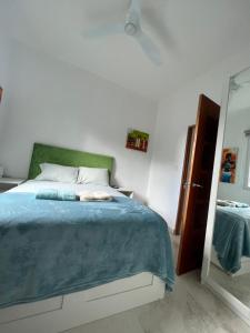 1 dormitorio con 1 cama con manta azul y espejo en JOY, en San Juan