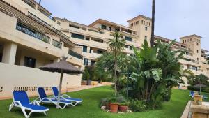 a yard with chairs and an umbrella and a building at Judith Apartment-Lovely duplex in Benalmadena in Benalmádena