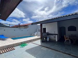 a patio with a swimming pool and a house at AeK Locações Casa Praia in Peruíbe