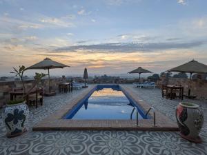 a swimming pool with tables and chairs and umbrellas at Nile Panorama Hotel in Luxor