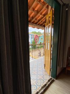 eine offene Tür eines Hauses mit Balkon in der Unterkunft Pousada Artes Evano in Bichinho