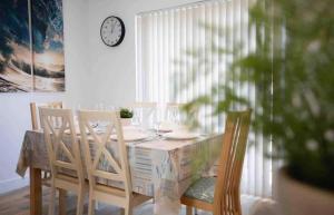a dining room table with chairs and a clock on the wall at Lundy SeaView Great Sea-views in Westward Ho +28 photos