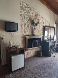 a living room with a tv and a stone wall at Evergreen Suites in Synikia Mesi Trikalon
