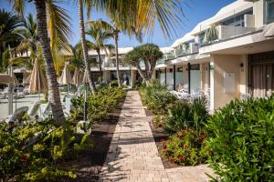 una passerella di fronte a un resort con palme di Apartamentos Las Buganvillas Adults Only a Puerto Rico de Gran Canaria