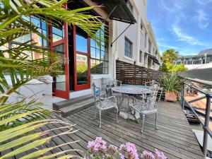 a wooden deck with a table and chairs on it at No load-shedding Spacious Apartment in Cape Town