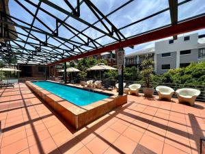 an outdoor swimming pool with chairs and umbrellas at No load-shedding Spacious Apartment in Cape Town