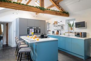 a kitchen with blue cabinets and a counter with stools at Brow Top Cottage, Penrith, Lake District in Skelton