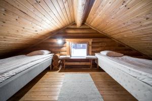 a attic room with two beds and a window at Peurasuvanto Mökit & Camping in Peurasuvanto