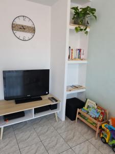 sala de estar con TV y reloj en la pared en Le Chanzy, en Le Beausset