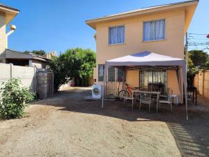 a house with a table and an umbrella in front of it at Casa a pocos minutos de playa La Herradura in Coquimbo