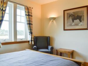 a bedroom with a bed and a chair and a window at Drummygar Mains in Carmyllie