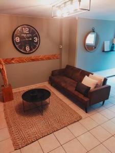 a living room with a couch and a clock on the wall at Nuitées / télétravail in Dunkerque