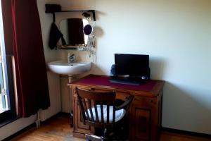 een badkamer met een wastafel en een bureau met een computer erop bij Onthaast & Geniet in Den Helder