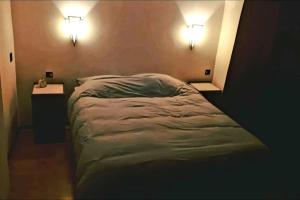 een bed in een kamer met twee lampen aan de muur bij Onthaast & Geniet in Den Helder