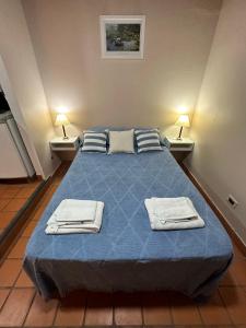 Un dormitorio con una cama azul con toallas. en Monoambiente Salta Centro en Salta