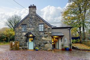 una casa de piedra con una puerta azul en una entrada en Ysgoldy, en Llanfor