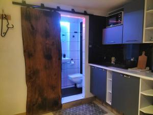 a bathroom with a toilet and a wooden door at 24h Gdynia Mini Apartamenty na kod dostępu & free parking & no keys in Gdynia