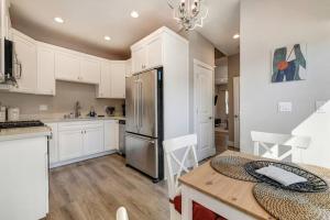 a kitchen with white cabinets and a table and a refrigerator at Sacramento Two-Story Condo Near Oak Park Brewing! in Sacramento