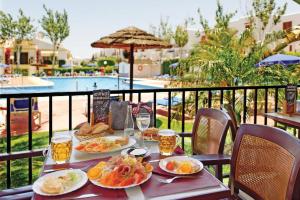 una mesa con platos de comida y bebida y una piscina en Verano Azul en Vera