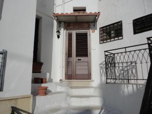 a white building with a wooden door and stairs at La Tana del Lupo in Oria