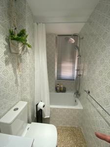 a bathroom with a white toilet and a bath tub at Apartamento Cebra in Zaragoza