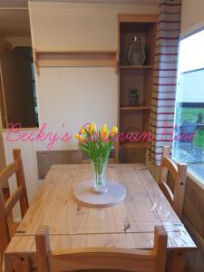 a wooden table with a vase of flowers on it at Becky's Caravan at Marton Mere in Blackpool