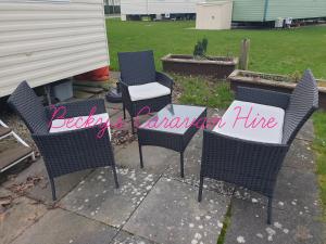 a patio with chairs and a table with a sign on it at Becky's Caravan at Marton Mere in Blackpool