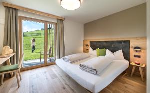 een slaapkamer met een groot wit bed en een groot raam bij Hoferhof in Maranza